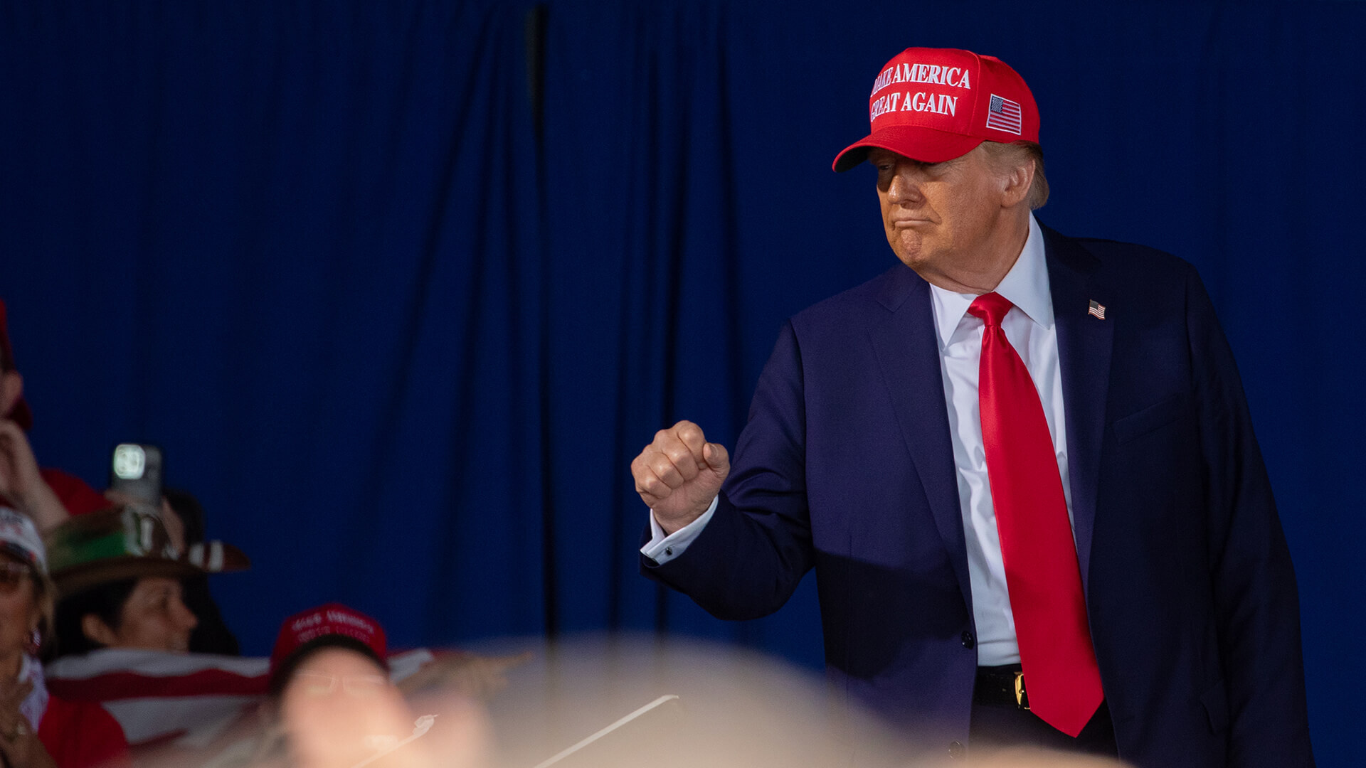 Donald J. Trump pokes outside bulletproof glass to pump his fist.