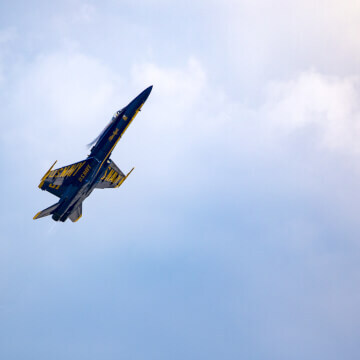 Blue Angel flying level at a reduced speed, with its nose pointed up.