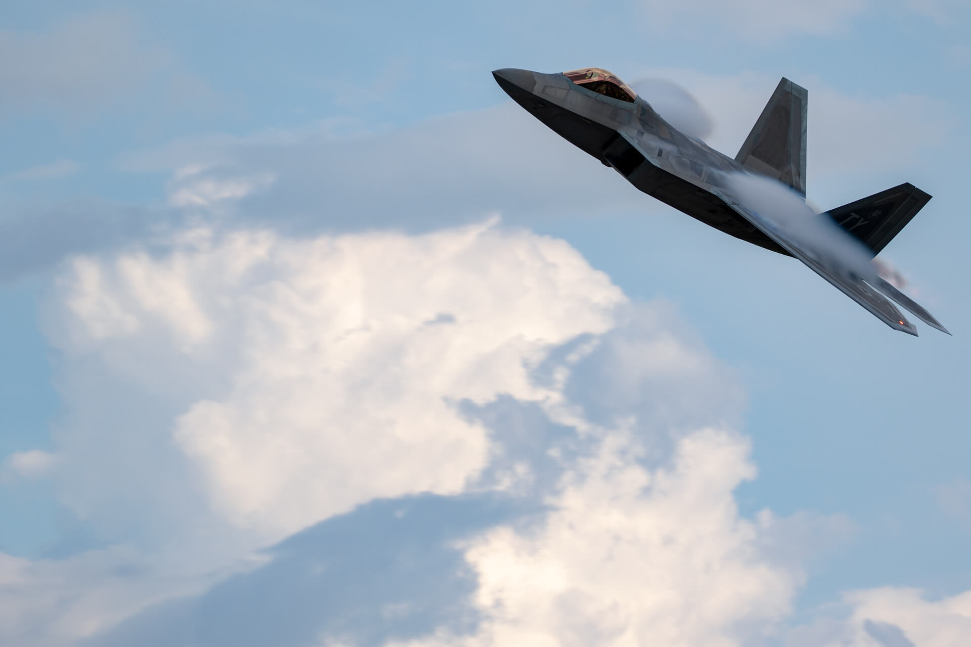 F-22 Raptor piercing the bright blue sky.