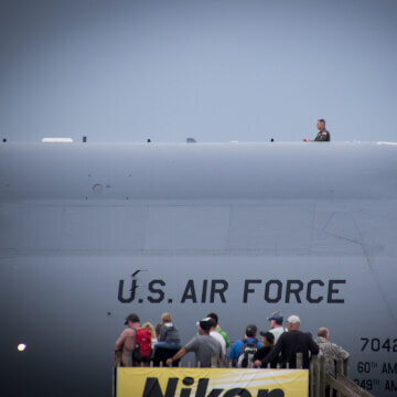 An airman enjoying the airshow from the top of the C-5M Super Galaxy; a U.S. Air Force heavy cargo transport.