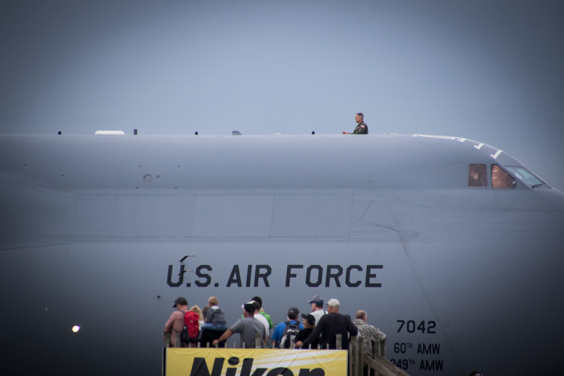 An airman enjoying the airshow from the top of the C-5M Super Galaxy; a U.S. Air Force heavy cargo transport.